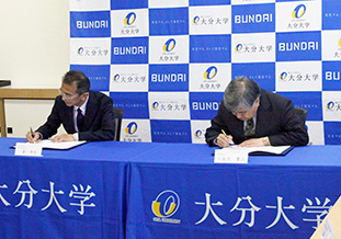 協定書にサインをする劉学部長（左）と<br />久能木専務理事（右）