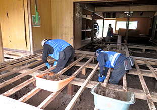 民家の床下の泥出し作業を行う学生<br />（7月22日九重町）