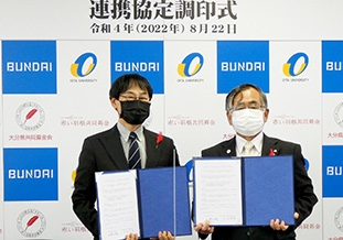 協定書を手にする北野学長(左)と三河会長(右)