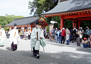 「放生会」で神職の列にシャッターを切る留学生