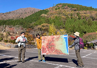 赤色立体図をつかって解説を行う荒井客員研究員(左)<br />（別府ロープウェイの別府高原駅）